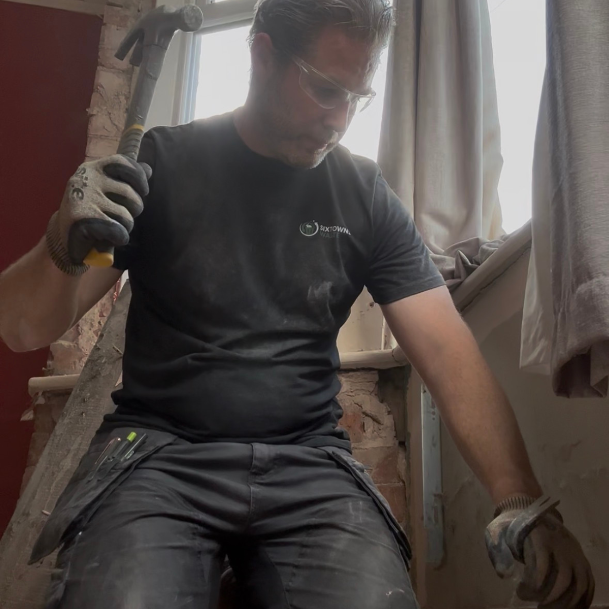 A worker using a hammer and pry-bar to remove skirting