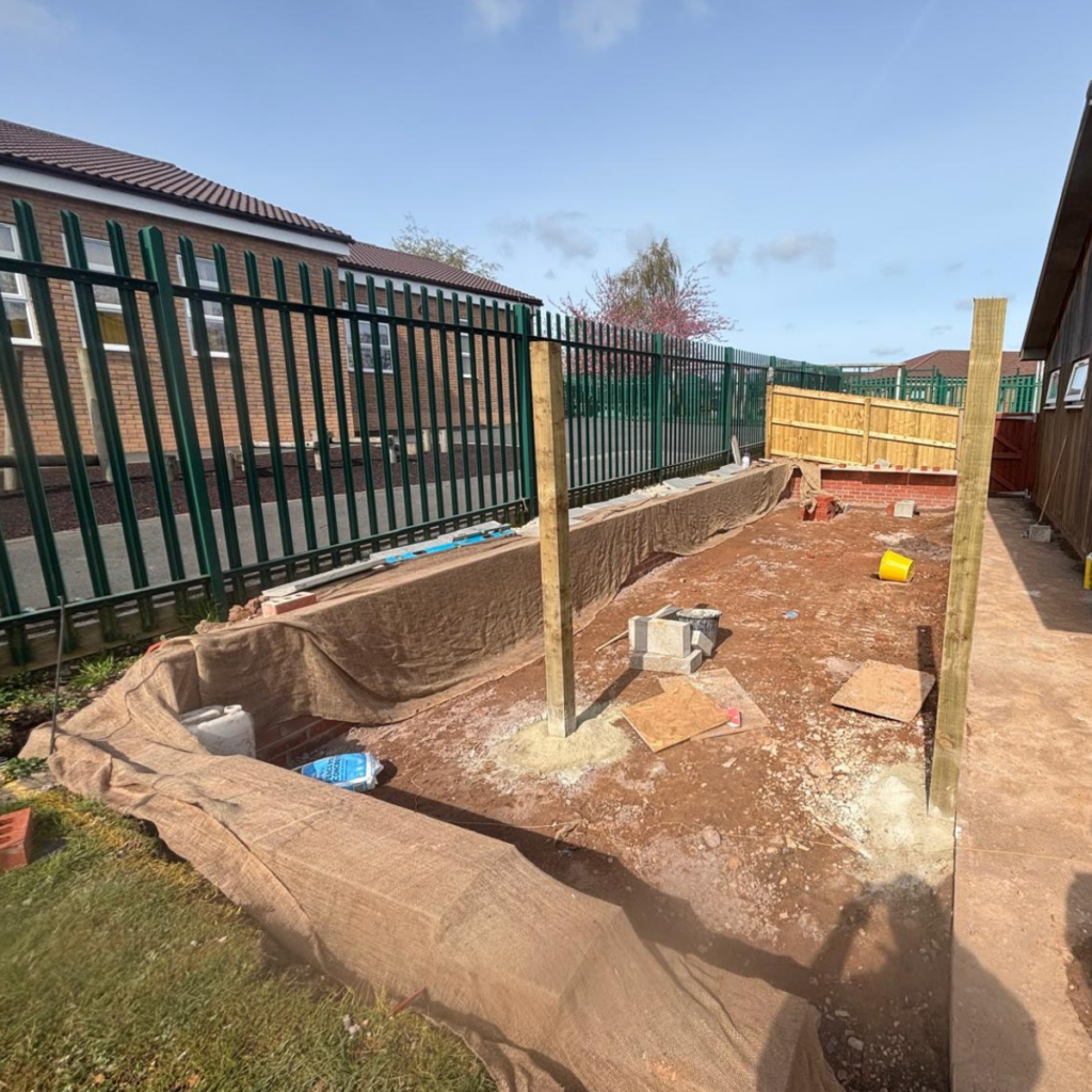 An area under construction showing a retaining wall and fence posts fitted.