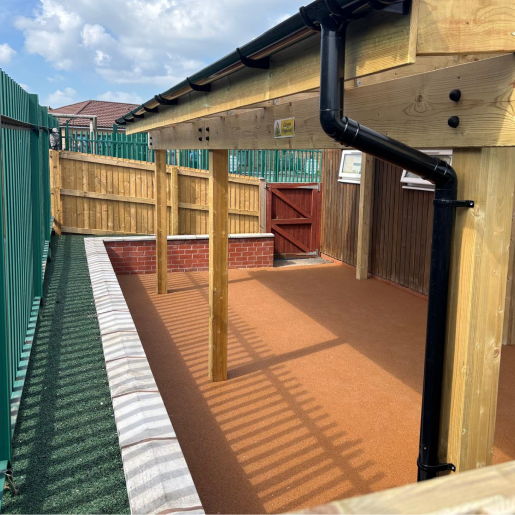 A newly installed outdoor classroom with wet pour rubberised floor, timber framed shelter and rubberised mulch edging.