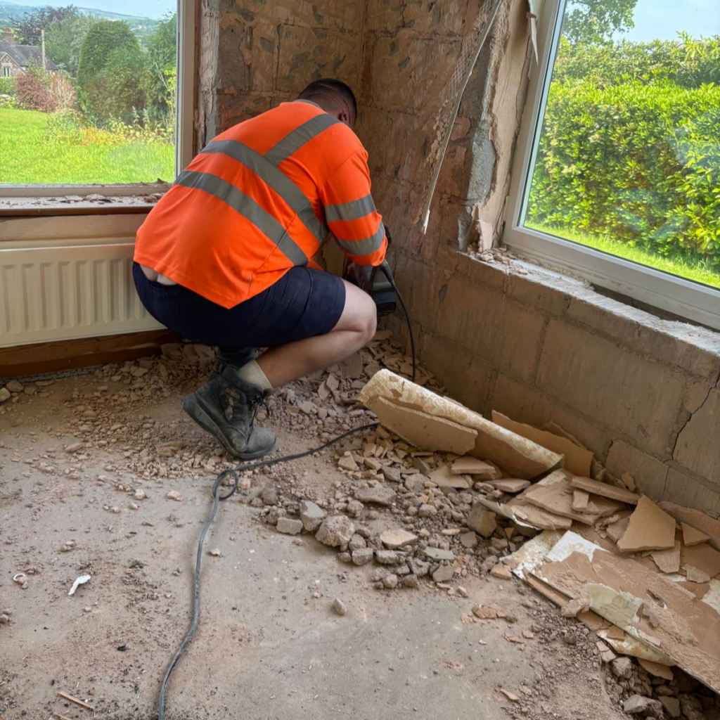 A contractor removing plaster from a wall.