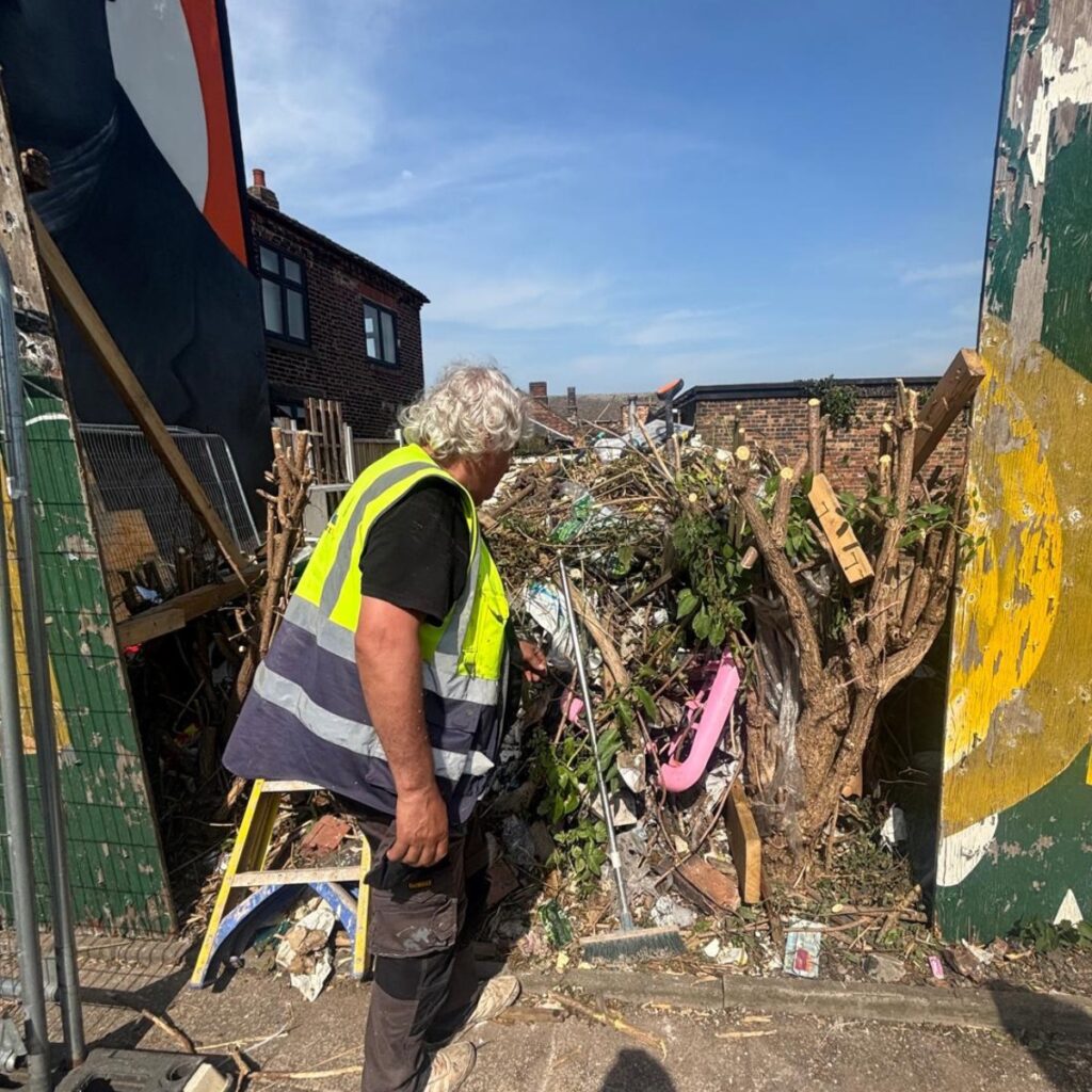 Operative clearing waste and overgrowth during a site clearance in Stoke-on-Trent