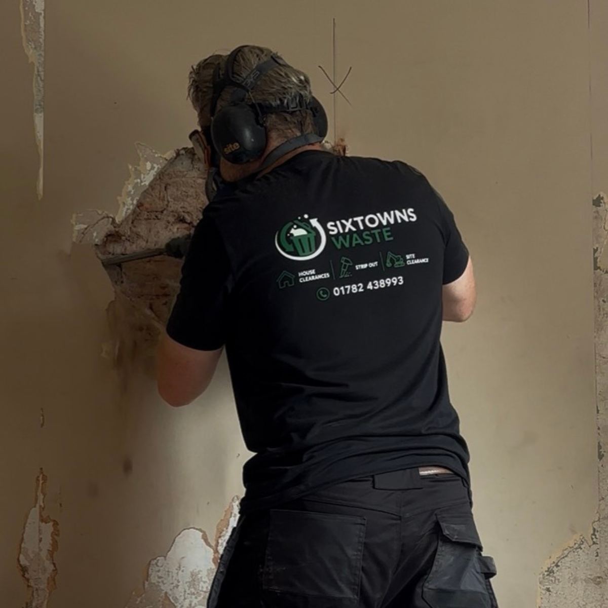 A worker stripping plaster off a wall in Stoke-on-Trent