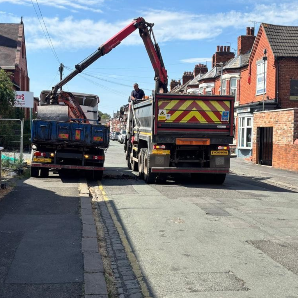 A grab lorry loading material from the back of a lorry.